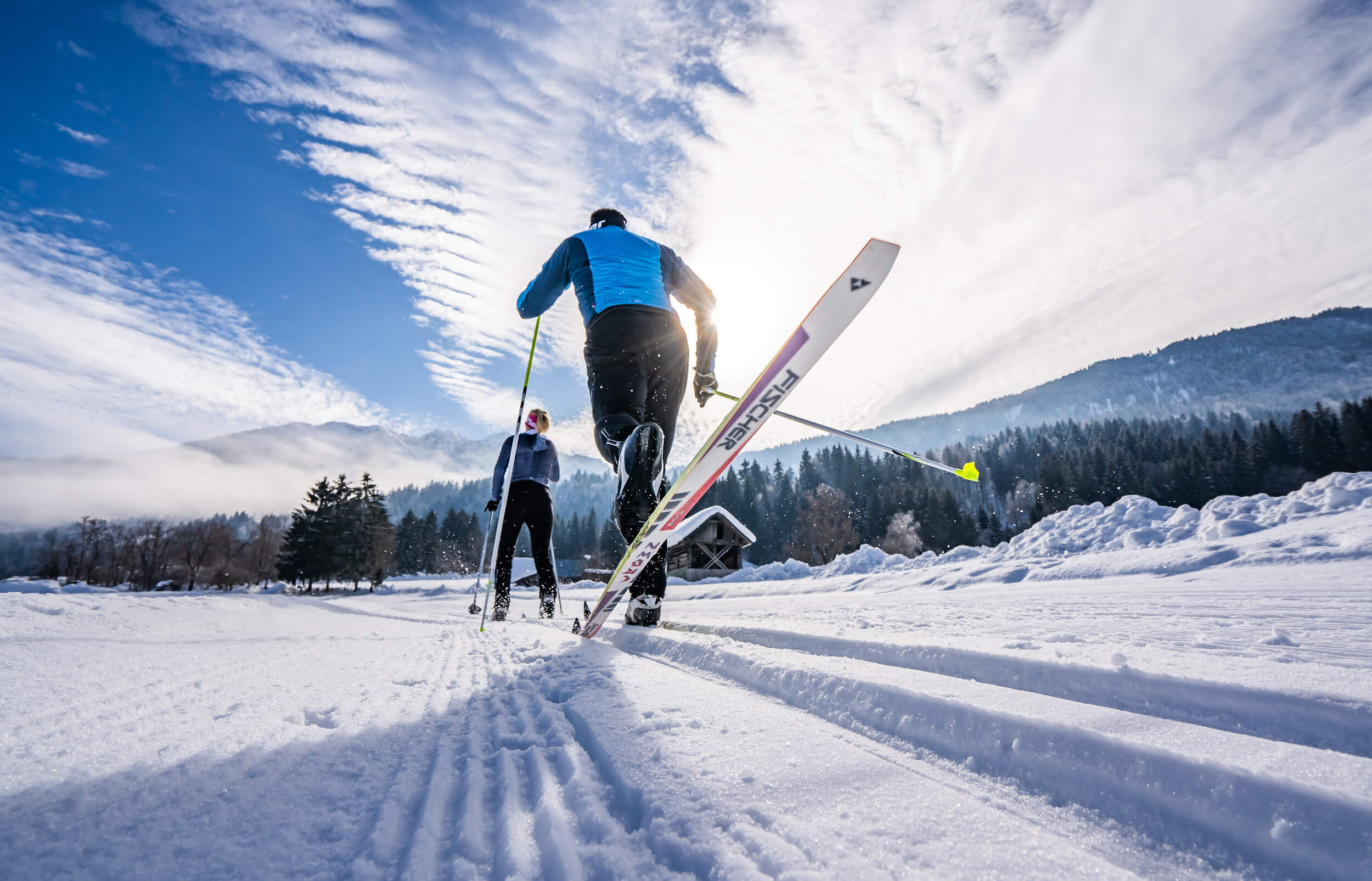 Zwei Langläufer fahren auf schneebedeckter Spur in winterlicher Landschaft