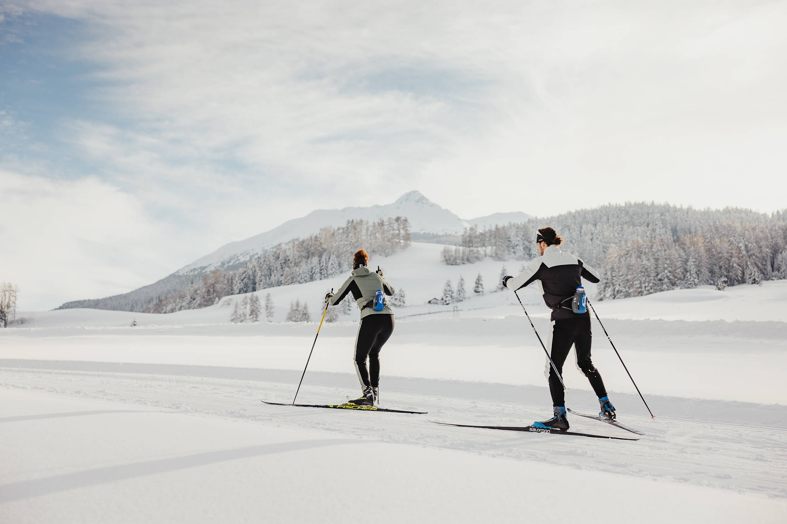 Zwei Personen beim Langlaufen in verschneiter Berglandschaft