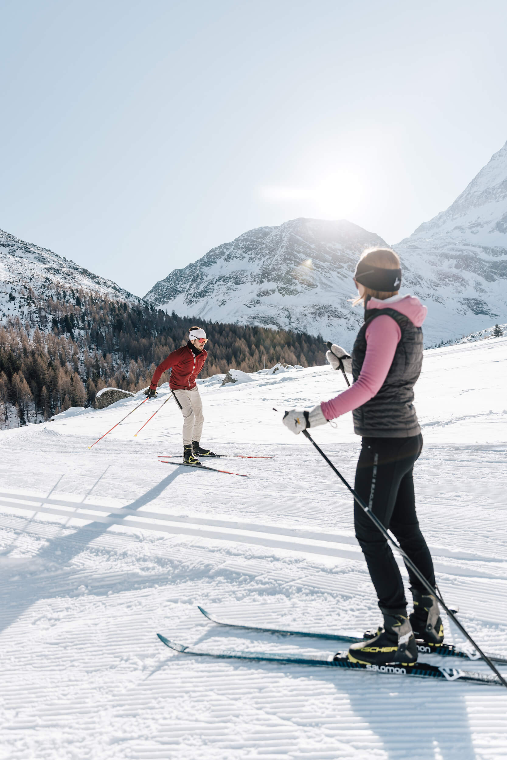 Zwei Menschen beim Langlaufen in den verschneiten Bergen bei Sonnenschein