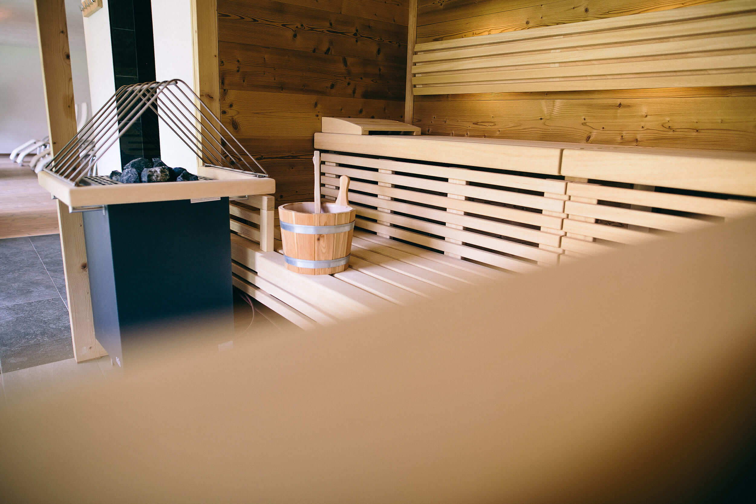 Innenraum einer Sauna mit Holzbänken und Saunaeimer